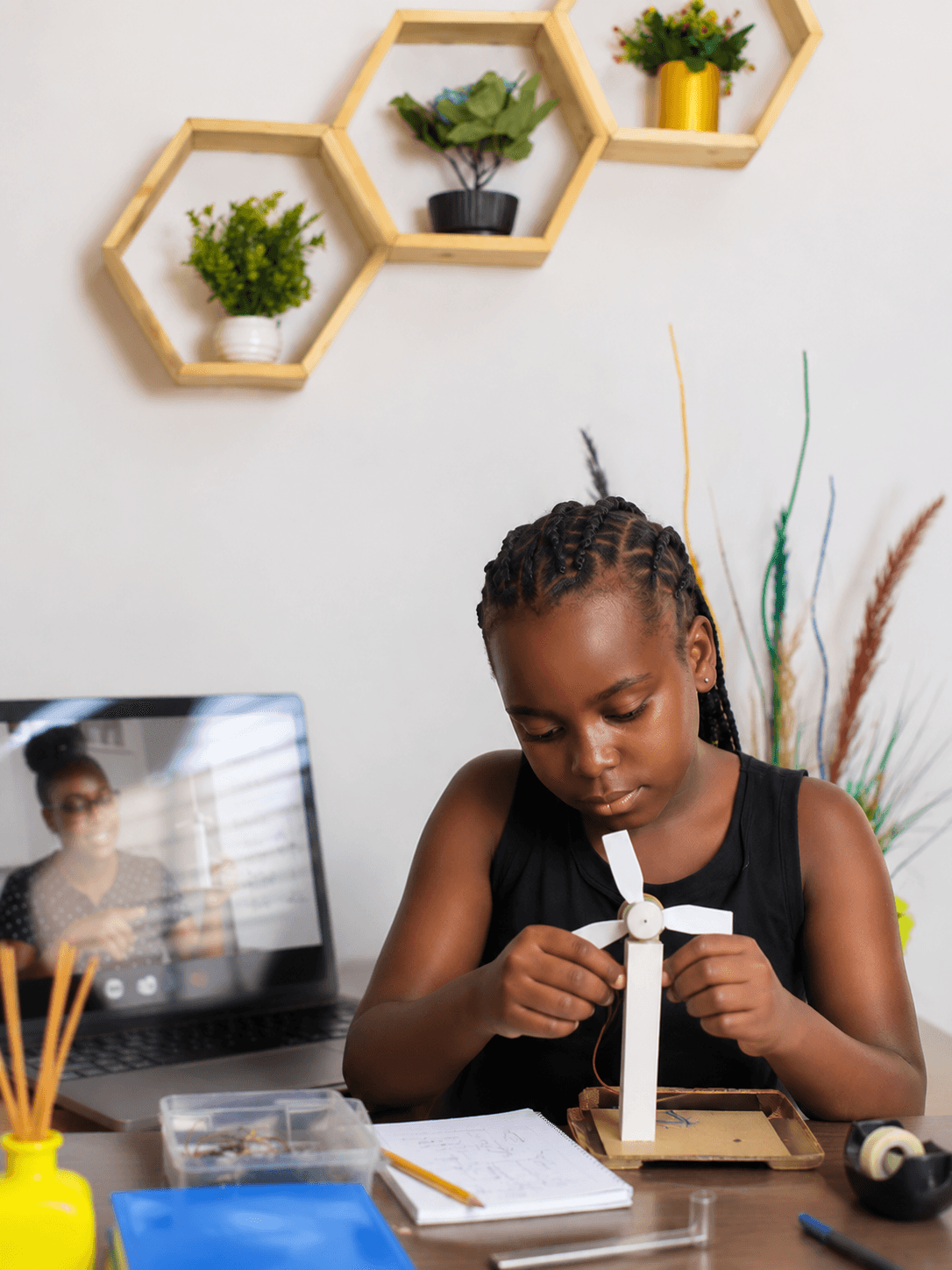 Girl building a small wind turbine craft project during an online class