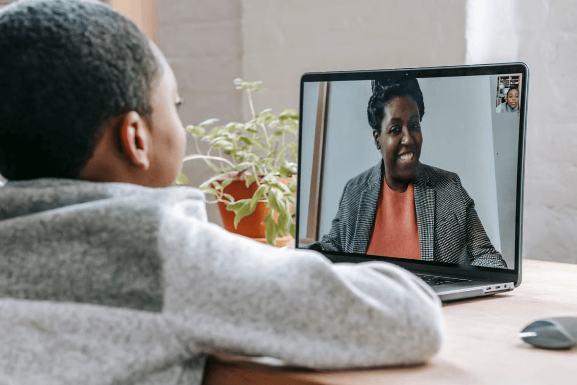 Child on a video call with a tutor on a laptop