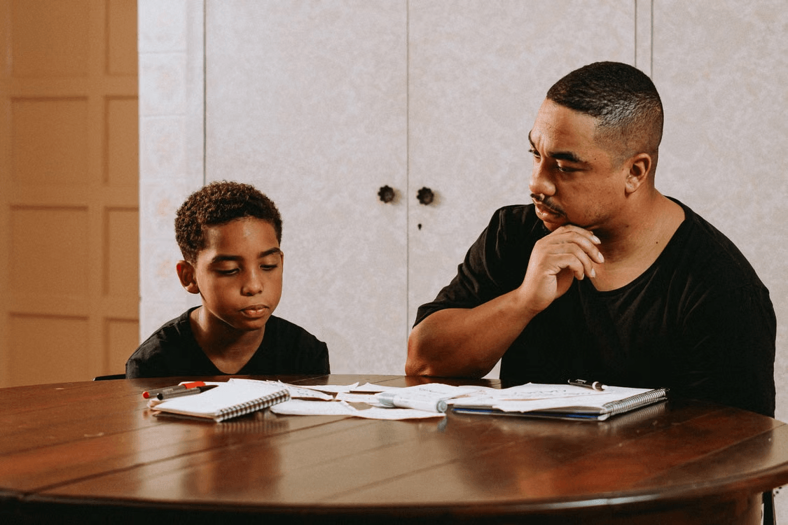 Father reviewing schoolwork with his son at the table