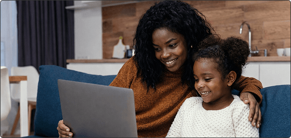 Mother and daughter looking at a laptop together on a couch